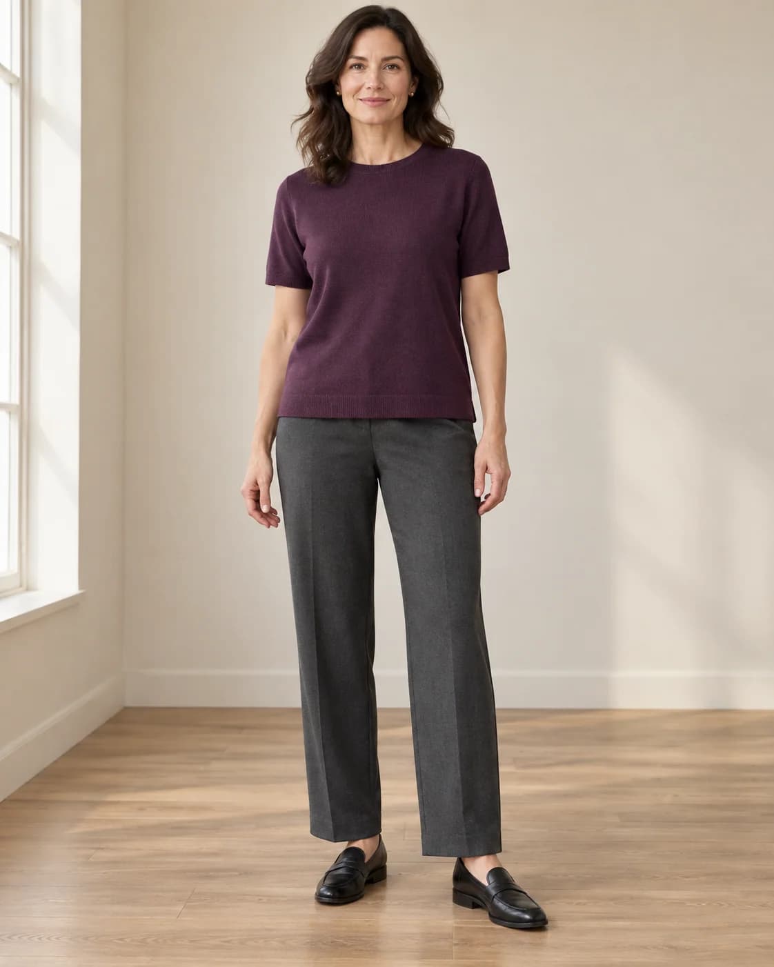 Plum short-sleeve knit worn untucked over charcoal ankle-length trousers with black loafers; the straight top hem covers the waistband.